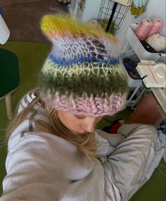 a woman wearing a knitted hat with multicolored yarns on the top