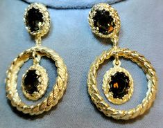 "Pair of marked 14K yellow gold dangle style pierced earrings. Each earring is set with two smokey quartz gemstones for a total of four smokey quartz gemstones set in the pair of earrings. Attached to the back of each earring is a 14K yellow gold post and with a 14K yellow gold friction fit back for fastening. The earrings are accented with a textured finish. Each earring measures approximately 1 1/2\" X 1\" X (1/4\" thick or depth) The top set smokey quartz gemstones set in each earring measure Classy Earrings, Quartz Gemstones, Earring Box, Quartz Earrings, Smokey Quartz, Fine Jewellery Earrings, Pierced Earrings, Earings Piercings, Earring Set