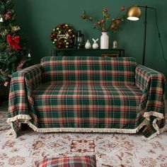 a couch covered in a tartan plaid blanket next to a christmas tree