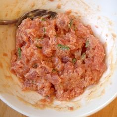 a white bowl filled with food on top of a wooden table next to a fork