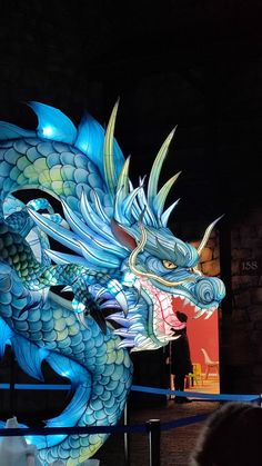 a large blue dragon statue sitting on top of a wooden table next to a wall