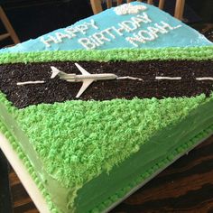 a birthday cake with green frosting and an airplane on the side that says happy birthday