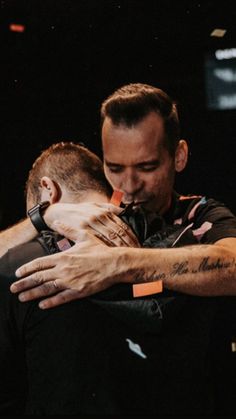 two men hugging each other in the dark