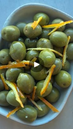 a bowl filled with green olives and orange peels