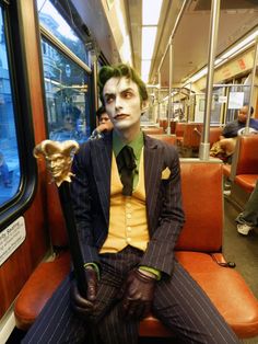 a man dressed as the joker sitting on a train