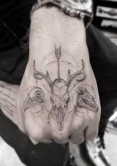 a hand with some tattoos on it and an animal's skull in the middle