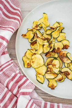 sliced zucchini on a white plate next to a red and white dish towel