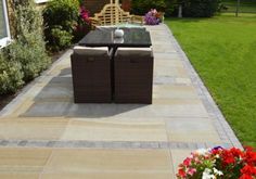 an outdoor patio with furniture and flowers in the foreground