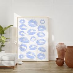 an art print with blue lips on it in a white room next to two vases