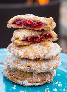 a stack of doughnuts sitting on top of a blue plate covered in powdered sugar