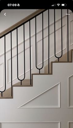 an open door and some stairs in a house with white walls, wood floors and black iron railings