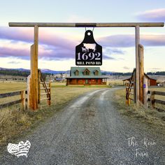 an open gate leading to a farm with a sign that reads, the road is paved