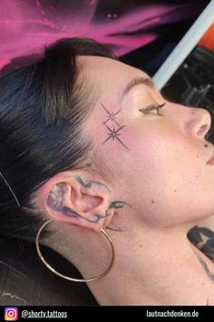 a woman with piercings on her ear and nose is looking at the camera while wearing large hoop earrings