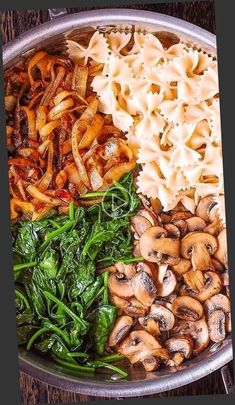 a pan filled with pasta, spinach and mushrooms