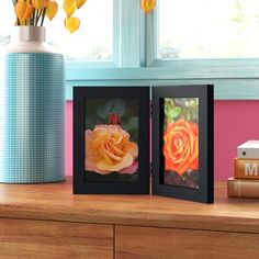 three frames with flowers in them sitting on a table next to a vase and books