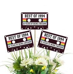 the best of 1994 sign is placed in a vase with daisies and greenery