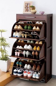 three tiered shoe rack in front of a potted plant on the floor next to a wooden bench