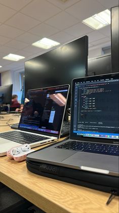 two laptops are sitting on a table in an office