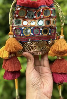 a hand holding up a small purse with tassels and beads on the inside