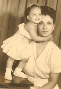 an old black and white photo shows a woman holding a child in her arms while posing for the camera