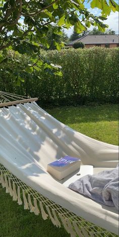 a white hammock sitting on top of a lush green field next to a tree