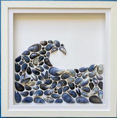 an art piece made out of shells with a wave in the middle and blue background