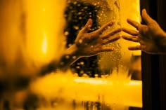 two hands reaching for each other in front of a mirror with water droplets on it