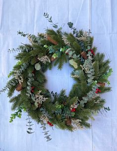 a christmas wreath with pine cones, berries and greenery