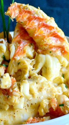 a bowl filled with macaroni and cheese covered in crab meat, garnished with parsley