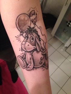 a person with a tattoo on their arm that has a dog holding a balloon in it's mouth