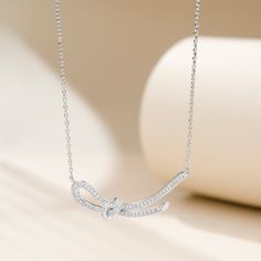 This necklace features a knot designed in the form of a ribbon, crafted with sterling silver. The delicate and elegant design of the pendant showcases the artistry and craftsmanship involved in its creation. The silky smooth texture of the ribbon adds a touch of sophistication to any outfit, making it a versatile accessory for both casual and formal occasions. This pendant necklace is a perfect choice for those who appreciate timeless elegance and desire to make a fashion statement.Carat Weight: Silver Bow Necklace For Wedding, Elegant Sterling Silver Necklace With Bow, Silver Sterling Silver Necklace With Bow, Elegant Sterling Silver Jewelry With Ribbon, Elegant Sterling Silver Infinity Necklace, Silver Ribbon Necklace For Gift, Elegant Bow Pendant Necklace, Formal Sterling Silver Ribbon Jewelry, Formal Sterling Silver Jewelry With Ribbon