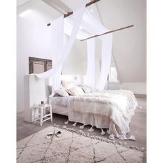 a white bedroom with a canopy bed and rug