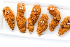 fried chicken with googly eyes are on a white platter, ready to be eaten