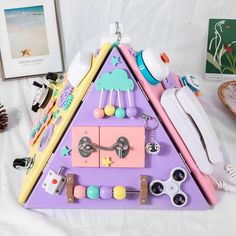 a purple and pink triangle shaped shelf with various items on it next to a pine cone