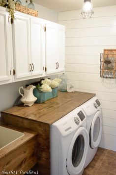 a white washer and dryer sitting in a laundry room next to some cabinets