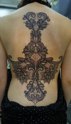 the back of a woman's body with an intricate tattoo design on her stomach