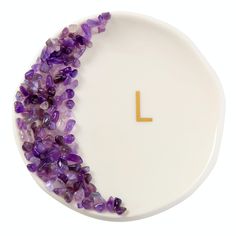 a white plate topped with purple beads and a letter l on it's side