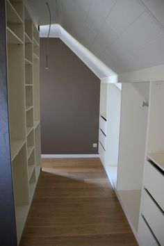 an empty room with white cabinets and wood flooring in the foreground is a large open closet