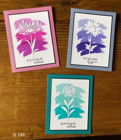 three cards with flowers on them sitting on a table