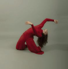 a woman in a red dress is doing an acrobatic pose on the floor