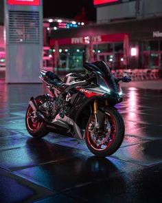 a motorcycle parked in front of a building on a wet street with neon lights behind it