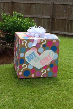 a box with a question mark on it sitting in the grass next to a fence