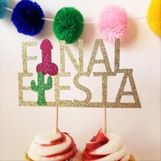 two cupcakes with white frosting and colorful pom - poms in front of a sign that says final fiesta