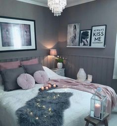 a bedroom decorated in grey and pink with pictures on the wall