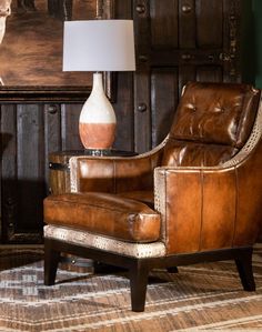 a brown leather chair sitting next to a lamp