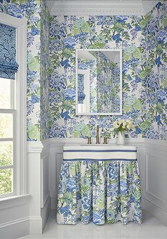 a bathroom with blue and green wallpaper, white fixtures and a sink in front of a mirror