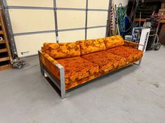 an orange couch sitting on top of a metal frame in a room filled with other furniture