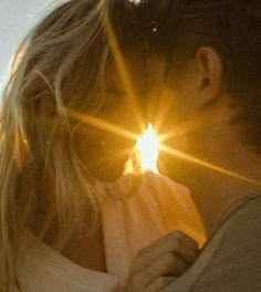 a man and woman kissing in front of the sun