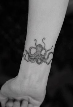 an octopus tattoo on the wrist is shown in this black and white photo, it looks like