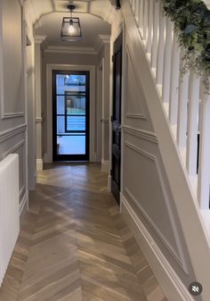 an empty hallway with wooden floors and white railings on either side of the door